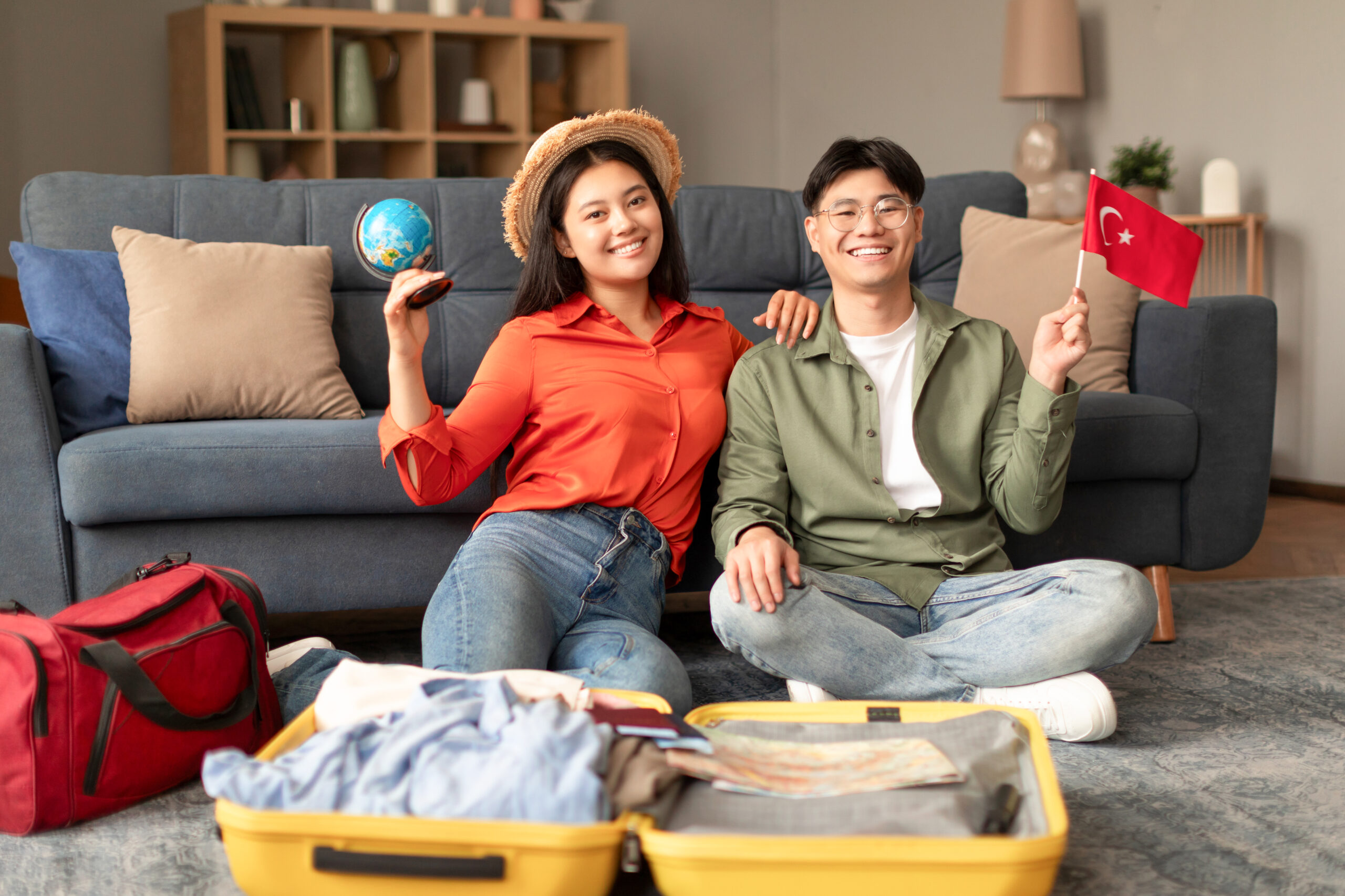 Japanese couple waving flag of Turkey holding globe packing indoor